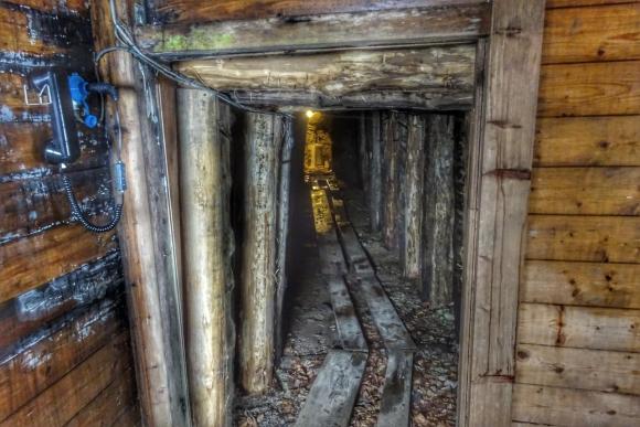 Interno d una galleria d una miniera, puntellata con travi di legno, con assi allineate sul terreno per far scorrere i carrelli