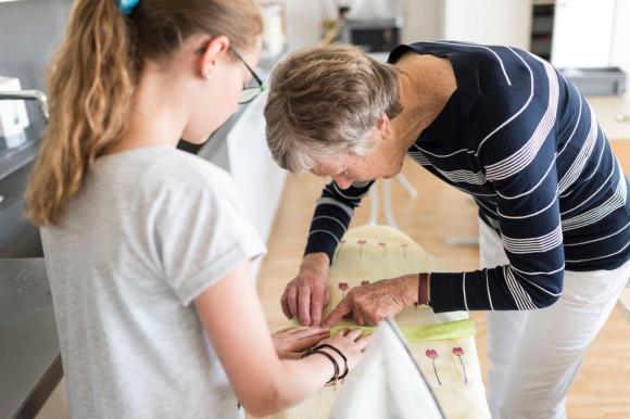 un anziana aiuta una ragazza e cucire un tessuto