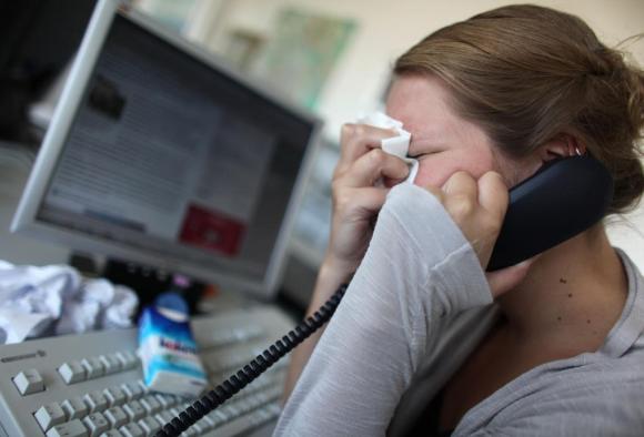Una donna piange mentre sta telefonando davanti a un computer