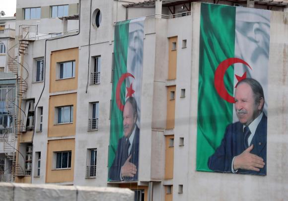 manifesti con la bandiera algerina e il viso di bouteflika su palazzi