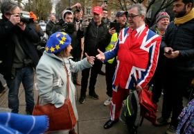 Una signora anziana con cappello raffigurante bandiera europea discute con signore che indossa abito raffigurante l Union Jack