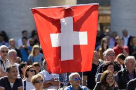 gruppo di persone con una grande bandiera svizzera.