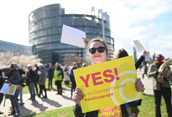 Una ragazza davanti al Parlamento europeo con tra le mani un cartello a favore della riforma