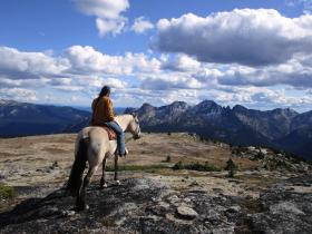 donna sul cavallo di fronte a un paesaggio esteso