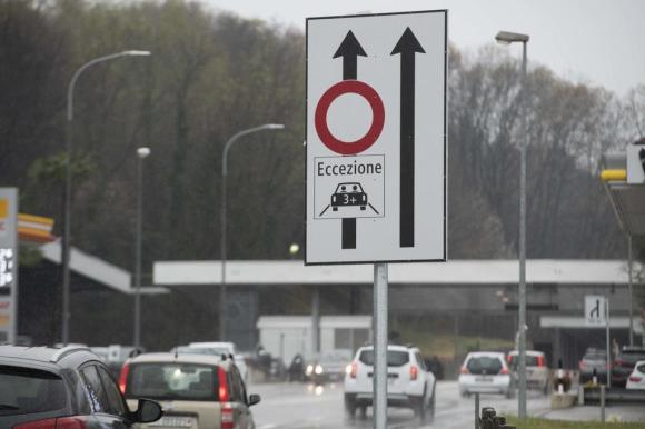 Un segnale stradale che indica una corsia dedicata ad automobili con almeno tre persone a bordo; sul fondo, auto sfocate