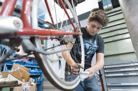 Ragazzino intento a riparare una bicletta in un officina meccanica