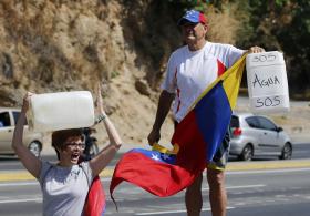 una donna e un uomo con la bandiera venezuelana e delle taniche per l acqua