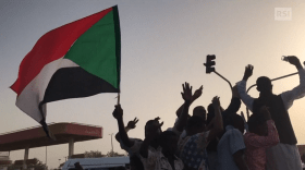 Immagini di dimostranti per strada all alba; sventolano bandiere sudanesi e fanno gesti di vittoria