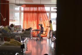 Una stanza d ospedale con arredi colorati e due pazienti bambine vista in controluce