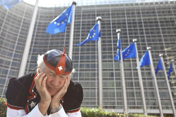 uomo con vestito tradizionale svizzero davanti a un edificio con bandiere europee