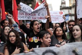 Primo piano di giovani in testa a un corteo di manifestanti con cartelli a favore dell educazione e contro il governo Bolsonaro.