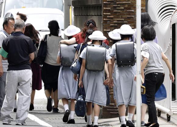 Bambine vestite da scolare in una strada di Tokyo