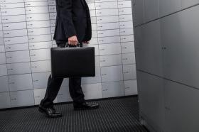 Uomo con valigetta nel reparto cassette di sicurezza di una banca.