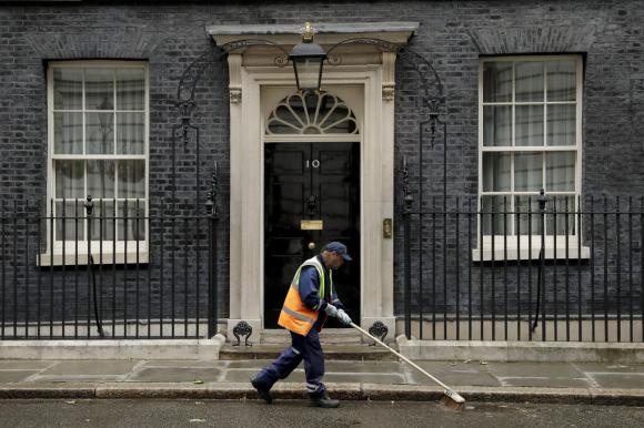 Un netturbino pulisce la strada davanti alla residenza del premier britannico in Downing strett