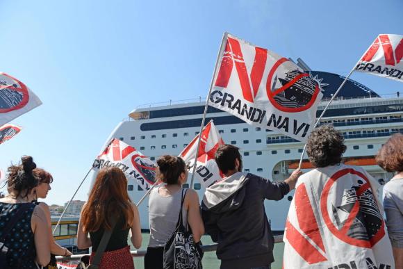 Giovani con in mano bandiere inneggianti contro le grandi navi da crociera