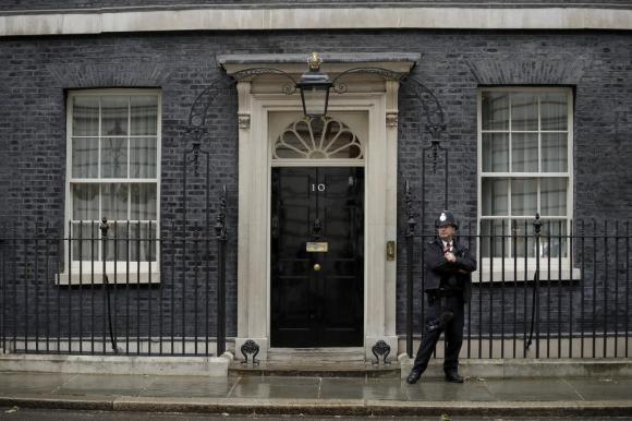 Veduta frontale dell ingresso della residenza al numero 10 di Downing Street; un poliziotto a destra del portone