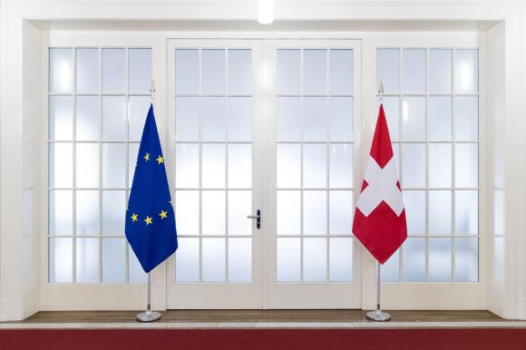 Due bandiere di piccolo formato, una dell UE l altra della Svizzera, posate col loro stativo sul davanzale di una finestra