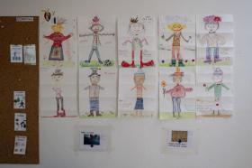 Disegni di bambini, effettuati da bambini, appesi a una parete bianca accanto a una bacheca
