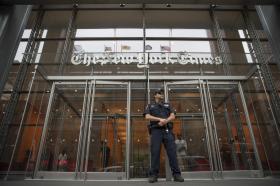 Ingresso di un edificio completamente a vetri con insegna New York Times e agente di sicurezza