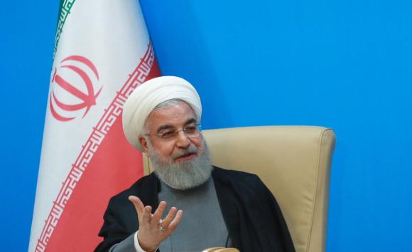 Una foto del presidente Hassan Rouhani con dietro una bandiera iraniana