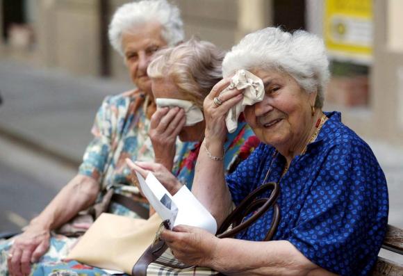tre anziane si asciugano la fronte con un fazzoletto