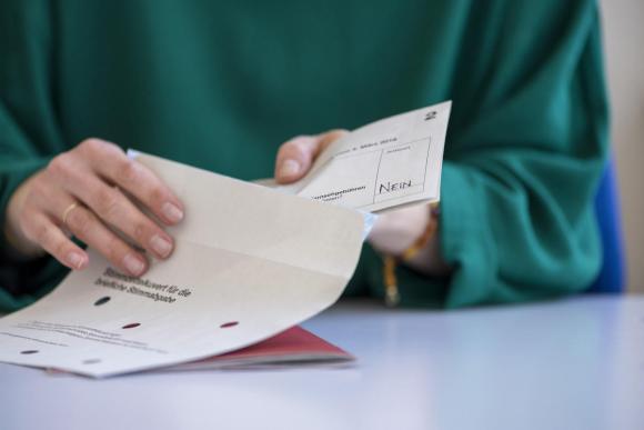 Persona infila una scheda elettorale in una busta.
