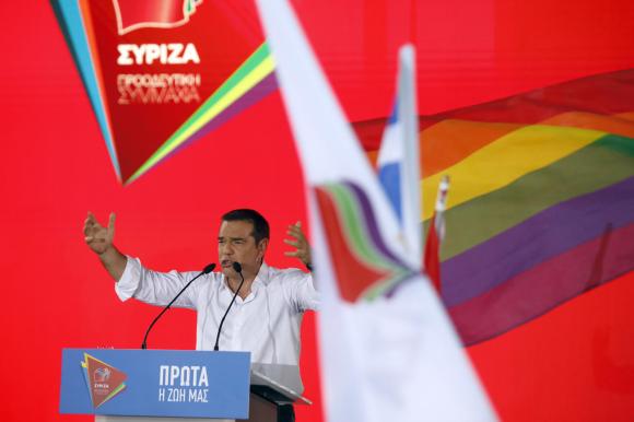 alexis tsipras dietro a due bandiere