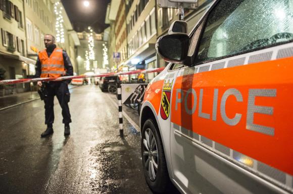 Un veicolo della polizia bernese posteggiata in città vecchia e sullo sfondo un poliziotto