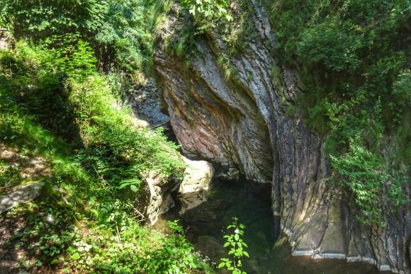 Immagine di un corso d acqua che scorre attraverso una gola tra due rocce; tutt attorno vegetazione verde