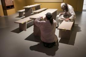 Tische und Bänke, zwei Handwerker beim Einrichten eines Museumsraums