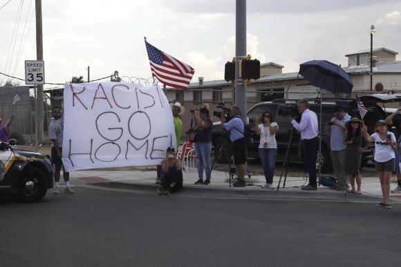 manifestanti con un cartellone sui cui sta scritto razzista, torna a casa