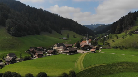 Veduta da lontano di un villaggio in una vallata; si intravvede il campanile; paesaggio collinare, verde, di campagna