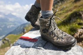 Walking boots on a rock with a mountain hiking trail sign