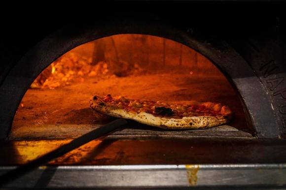 Una pizza mentre viene tolta da un forno a legna. Una foto scattata in una pizzeria di Napoli.