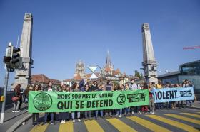 Imbocco di un ponte monumentale con gruppo di dimostranti disposto di traverso e striscione ambientalista