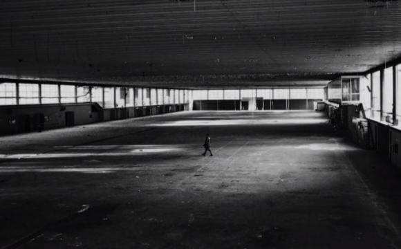Un fotogramma del documentario: il regista piccolo piccolo in un capannone industriale completamente vuoto e fatiscente