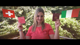 Immagine a mezzo busto di una signora sulla 50ina che tiene in una mano un passaporto svizzero nell altra uno italiano