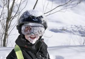bambino sorridente con il volto e il capo coperto di neve