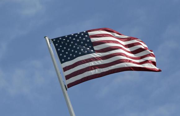 La bandiera americana in primo piano e dietro un cielo azzurro e limpido.