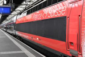 Motrice di un treno con la scritta France <> Suisse ritratta di traverso; si vede poco della stazione