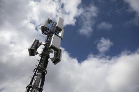 Antenna di telefonia mobile vista dal basso, circondata da nuvole - sulla dx porzione di cielo terso