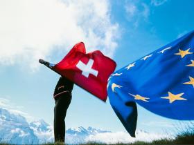 Uno sbandieratore con le bandiere di Svizzera e Unione europea