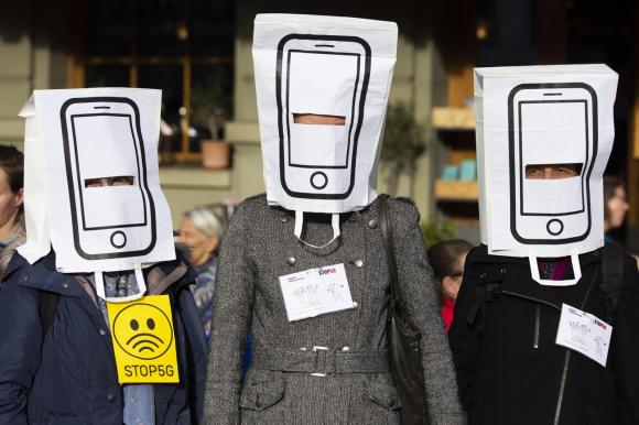 Manifestanti contro il 5g: in questo caso tre persone con dei sacchetti in testa a forma di telefonino e cartelli contro il 5g