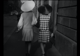 Riprese di schiena, per la strada, 2 donne con tailleur che indossano copricapo da raccoglitrice di riso.