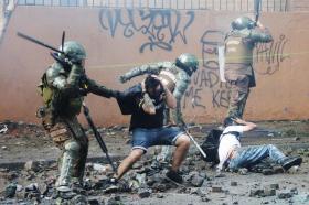 Un militare trattiene e picchia un civile mentre un altro civile è a terra picchiato da un altro militare