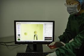 Una donna con camice, guanti e mascherina mostra immagini di un esperimento al computer