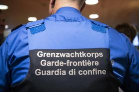 Primissimo piano di una guardia di confine, ripresa di spalle; scritta Grenzwachtkorps ecc. sul gilet