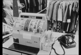 Primo piano di un vecchio registratore di cassa e di un telefono da tavolo in bachelite, in un negozio di vestiti.