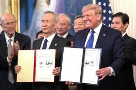 Trump e Liu mostrano ai fotografi l accordo firmato, attorniati da alti funzionari; sul fondo bandiera USA