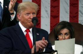 Mezzo busto di Trump che sorride e applaude, sfuocato; dietro, a fuoco, Nancy Pelosi guarda perplessa semi-coperta da un foglio